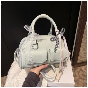 Detail of mint green Boston bag with lace bows and decorative front pockets