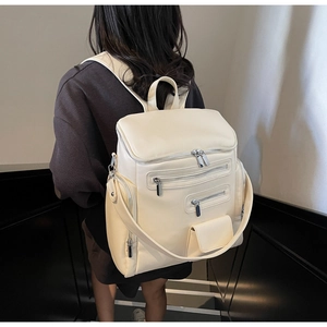 Detail of a creamy white large capacity faux leather backpack with multiple zipper pockets