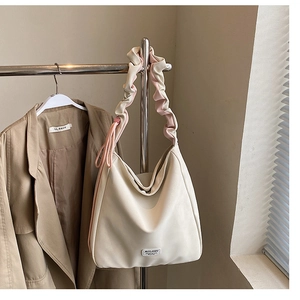 Detail of off-white tote bag featuring unique ruched straps and a minimalist brand label