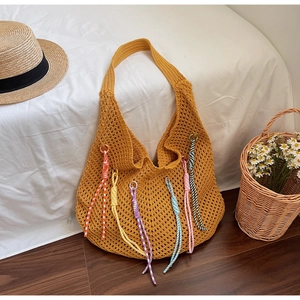 Detail of a ginger yellow hollow crochet hobo bag with vibrant colorful bohemian tassels