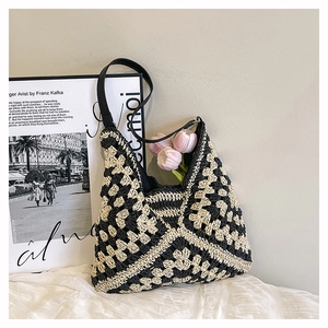 Close-up of handmade straw tote with black contrast patterns and leather strap