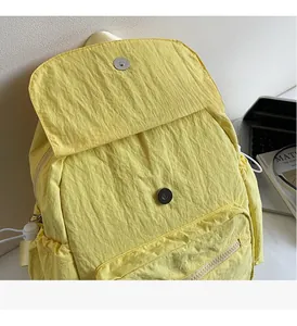 Detail of light yellow backpack with crinkled nylon fabric and metal buckle closure