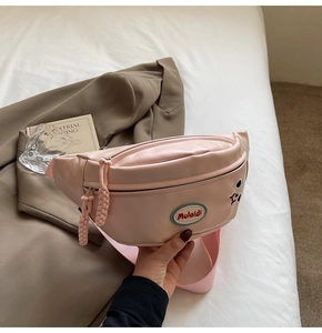 Dettaglio borsa pettorale in pelle PU rosa con ricamo e toppa con logo Mulaidi
