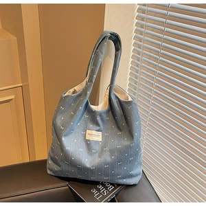 Detailed interior view of a large blue denim tote bag with white bow patterns on a bench