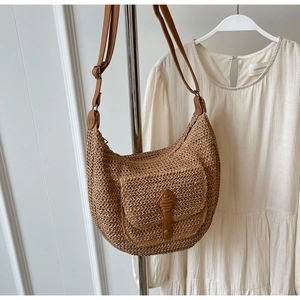 Macro detail of paper straw shoulder bag with adjustable strap and front flap pocket