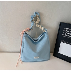 Detail of light blue tote bag featuring ruched handle and pink side drawstring decoration