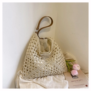 Detail of hollow woven shoulder bag featuring beige crochet patterns and leather strap