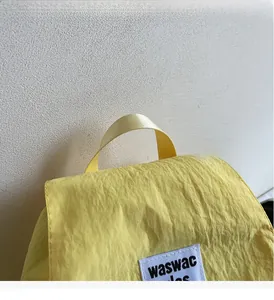 Close-up of lightweight yellow wrinkled nylon fabric with sturdy handle and brand label