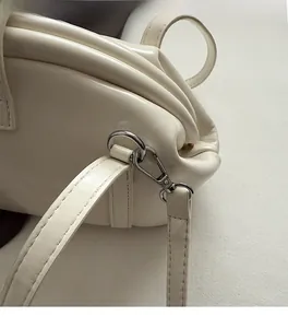 Détail du sac bandoulière crème avec ferrures métalliques élégantes et coutures précises