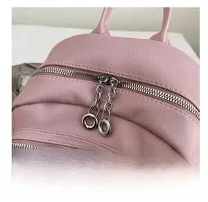 Macro detail of smooth dual metal zippers on pink lychee grain leather backpack