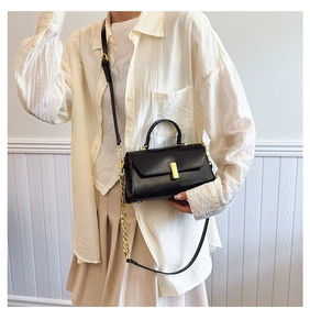 Classic black leather square handbag with gold metal clasp shown on model at 45 degree angle