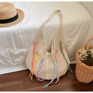 Detail of hollow knit beach tote with colorful tassels and a bohemian summer design