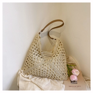 Detail of hollow crochet straw bag with beige fabric lining and brown leather strap