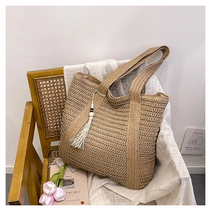 Detail of straw tote bag with white tassel charm on vintage chair with tulips