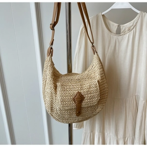 Detailed macro view of woven straw beach bag featuring a leather flap and magnetic buckle