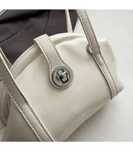 Gros plan du sac bowling en cuir crème avec un fermoir rotatif en métal argenté et coutures