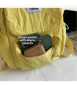 Detail of yellow backpack front zipper pocket showing storage for phones and wallet