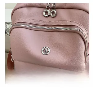 Close-up of pink lychee grain leather backpack with silver zippers and circular metal logo