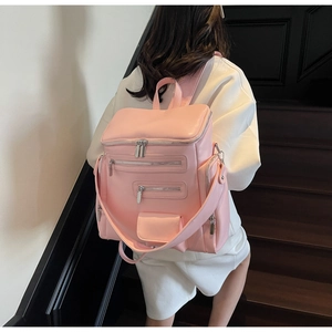 Detail of the multi-pocket pink leather backpack showing zippers and layered storage