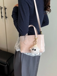 Sac seau rose minimaliste avec bandoulière réglable et breloque peluche en situation