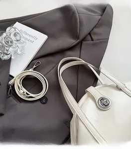 Détail d'un sac bowling en cuir blanc brillant avec fermoir rotatif et bandoulière