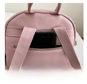 Close-up of the anti-theft back pocket on a pink pebbled faux leather backpack with a phone