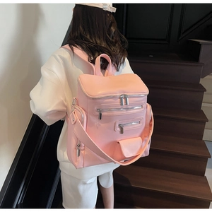 Rear view of a pink multi-pocket PU leather backpack worn by a model in a minimalist setting