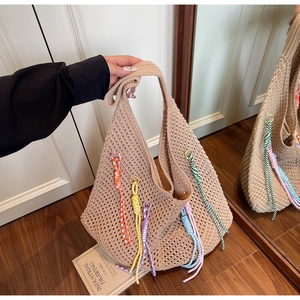 Close-up of hollow knit beach tote with colorful braided tassels and bohemian design details
