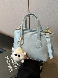 Sac seau bleu clair avec finitions dorées et charmant monstre en peluche blanc