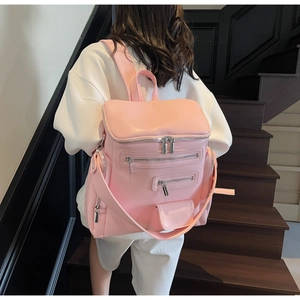 Detail of pink PU leather backpack showing multiple functional pockets and matte texture