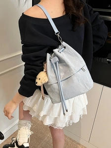 Light blue drawstring bucket bag with a cute puppy pendant shown on a model
