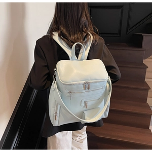Rear view of a light blue multi-zipper leather backpack being worn on model stairs