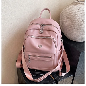 Macro detail of pink textured leather backpack with metallic logo and patterned strap