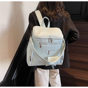 Detailed back view of a light mint green multi-pocket backpack worn over a black blazer