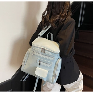 Detail view of light blue fashion backpack with multiple pockets and silver hardware