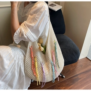 Detail of crochet knit beach tote bag with colorful tassels and hollow grid pattern
