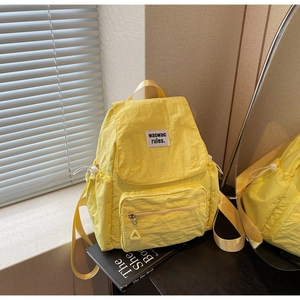 Dettaglio dello zaino in nylon giallo brillante con etichetta quadrata e tasca con coulisse