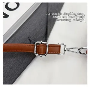 Detail of adjustable brown leather shoulder strap with silver metal buckle and lobster clasp