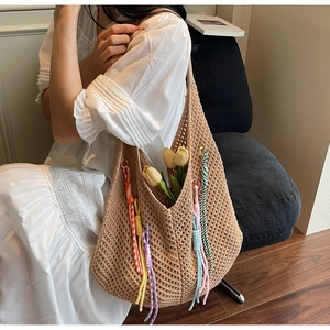 Detail of beige hollow crochet tote bag with colorful tassels and floral decoration