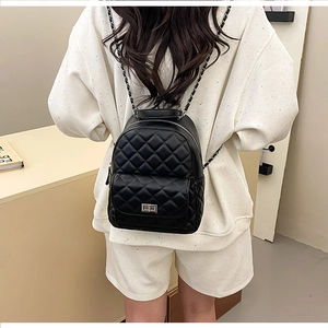 Detail eines schwarzen Mini-Rucksacks mit Rautensteppung, Silberkette und Drehverschluss