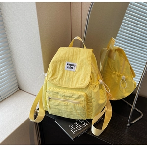 Dettaglio di uno zaino in nylon giallo con tasche a coulisse ed etichetta del marchio