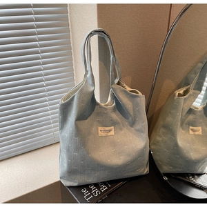 Detail of light blue corduroy tote bag with bow embroidery and branded fabric patch