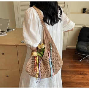 Close-up of woven straw shoulder bag featuring colorful tassels and hollow knit detail