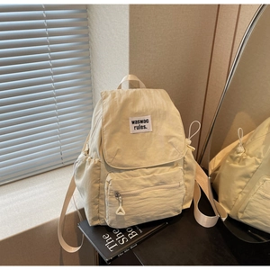 Dettaglio dello zaino in tela crema con toppa intrecciata e tasche laterali con coulisse