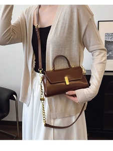 Retro dark brown leather crossbody bag with gold buckle and chain strap shown on model
