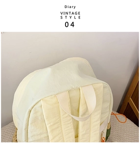 Detail view of the lightweight cream nylon backpack featuring orange cord accents and straps