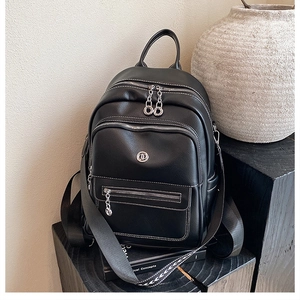Detailed close-up of black leather backpack with silver zippers and contrast white stitching