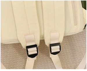 Detail of adjustable padded shoulder straps and nylon webbing on a cream travel backpack