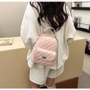 Rosa gesteppter Mini-Rucksack mit silbernen Kettenriemen am Model in modernem Interieur