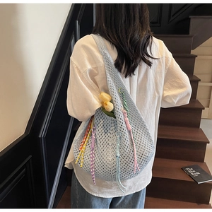 Detail of light blue knit hobo bag with colorful braided cord and hollow design texture